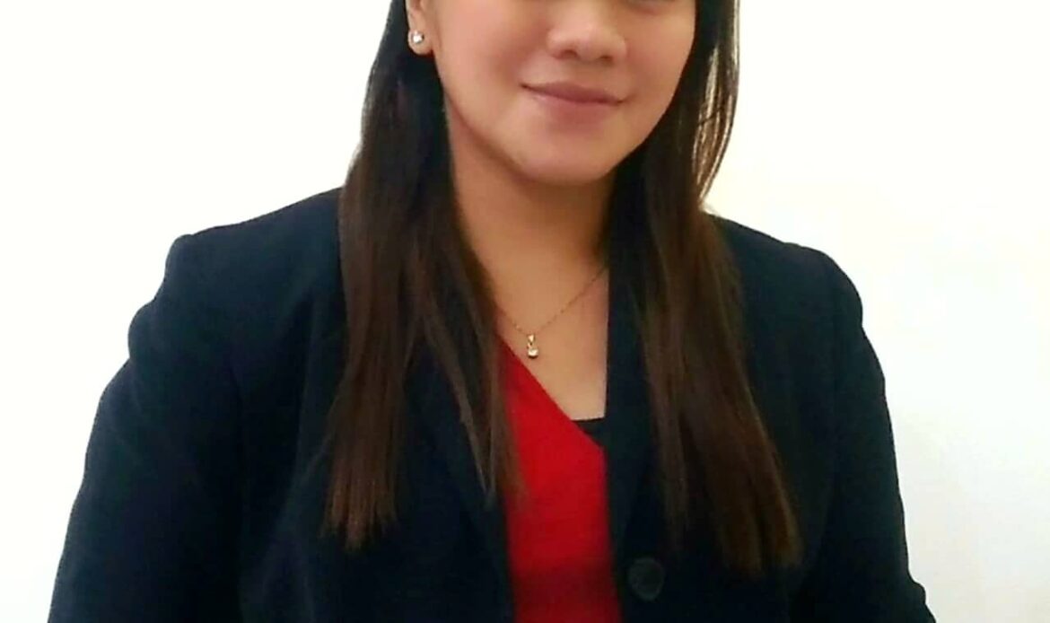Woman in black blazer, red shirt smiling.